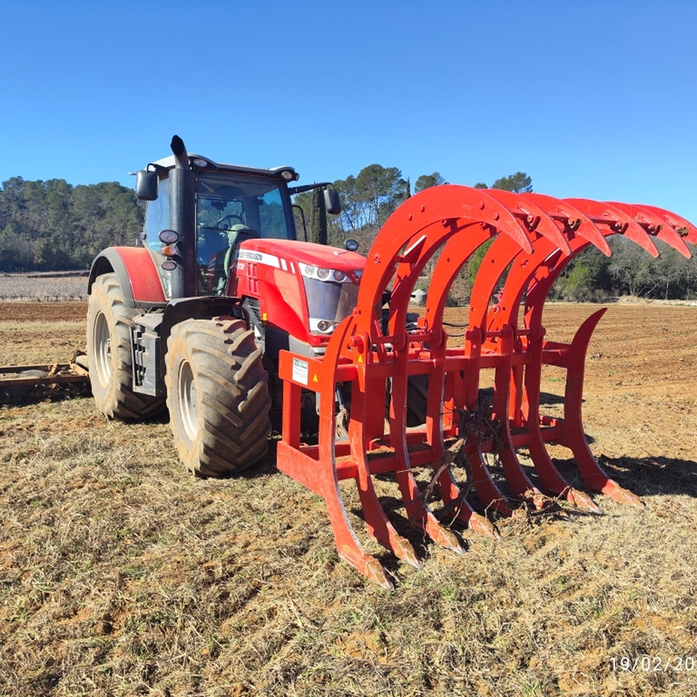 Massey Ferguson : Tracteur avec Grappin de Défrichage Tracteur Massey Ferguson rouge équipé d'un grappin frontal à griffes géant pour le défrichage agricole.